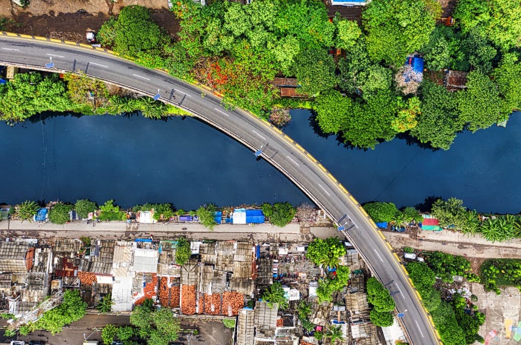 An aerial view of a bridge crossing a river between forest and town